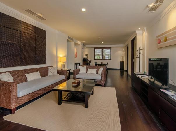 Amplio salón con sofás de ratán y televisión del Ruby Nusa Dua Bali con suelos de madera oscura