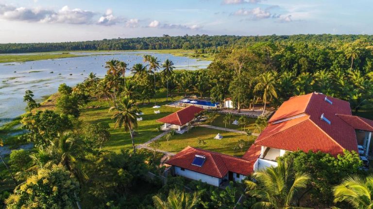 Vista aérea de The Notary's House rodeada de palmeras, jardines tropicales y lago natural en Sri Lanka