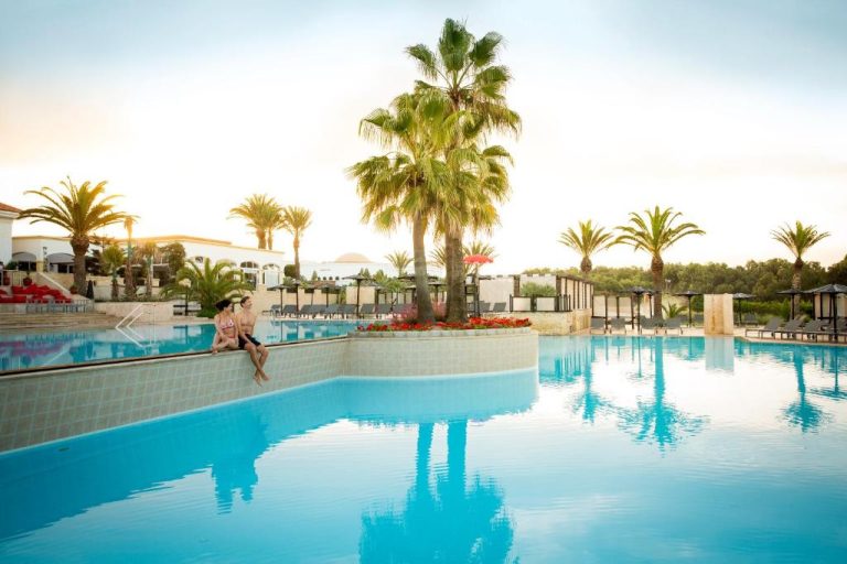 Amplia piscina exterior con palmeras y tumbonas del Robinson Agadir All Inclusive al atardecer