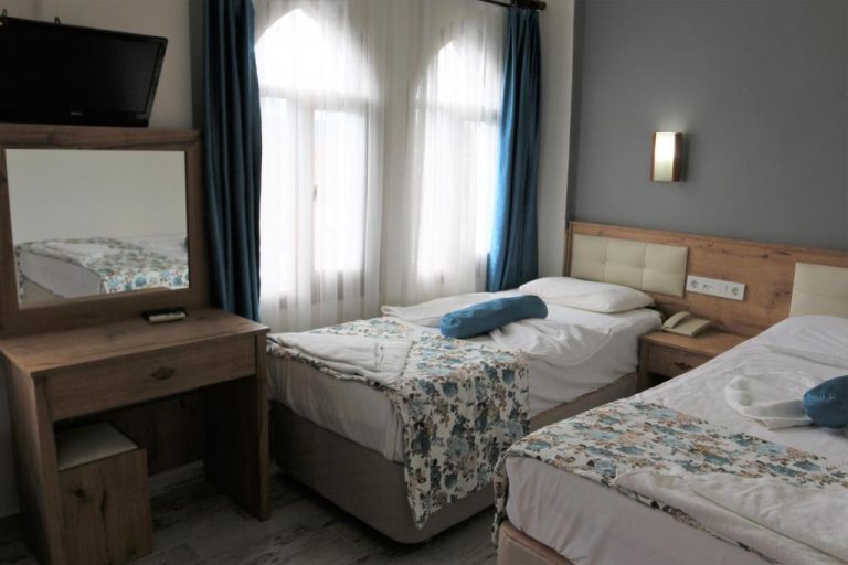 Habitación triple con tres camas individuales y decoración en madera del Eroglu City Hotel