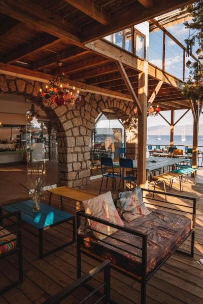 Terraza bar con arco de piedra y vistas al mar del Hotel L'Escale con veleros al fondo