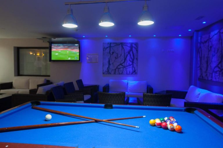Sala de billar con iluminación azul, sofás y televisión en el Grupotel Revoli