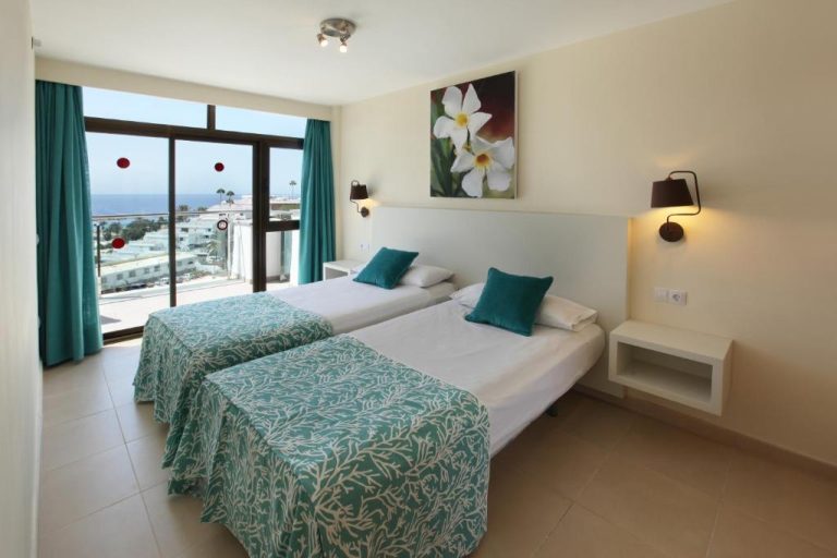 Habitación doble con dos camas y vistas al mar en el Grupotel Revoli, decoración en tonos turquesa