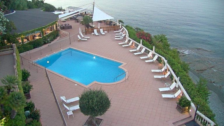 Piscina exterior con tumbonas y vistas al mar del Hotel Alivi en terraza frente al océano