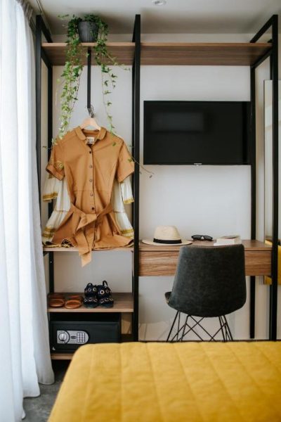 Habitación con armario abierto, escritorio y televisión del Cosmo Napa Boutique Hotel