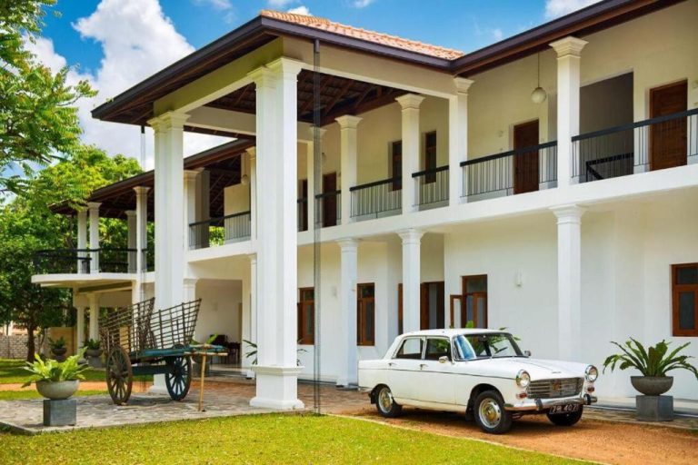 Fachada exterior colonial de The Notary's House con coche clásico blanco vintage y jardín tropical