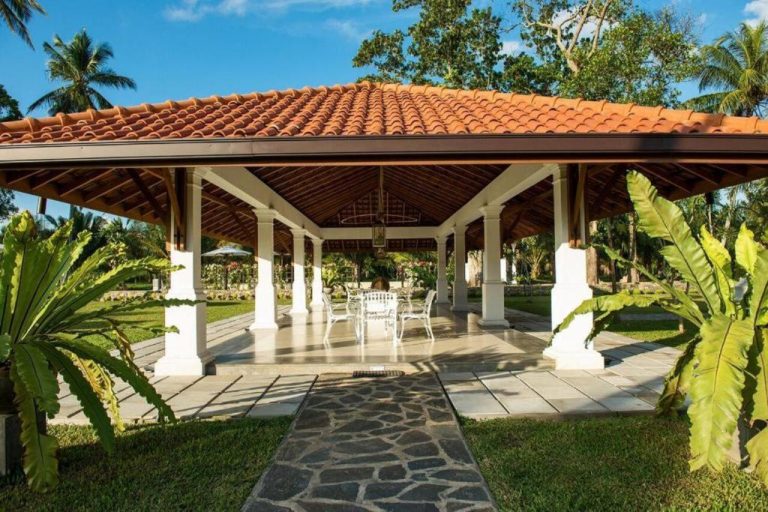 Gazebo colonial con mesa y sillas blancas rodeado de jardín tropical en The Notary's House