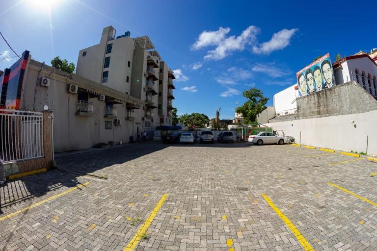 Estacionamiento exterior con pavimento de adoquines del Hotel Renacer bajo cielo azul despejado