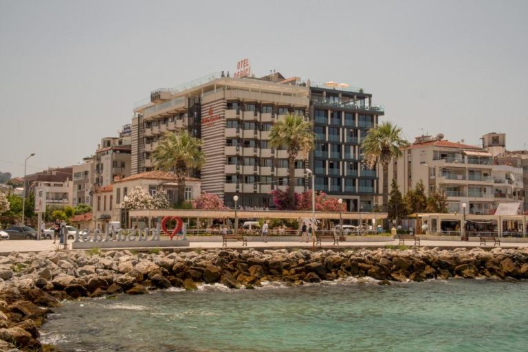 Vista exterior del Derici Hotel frente al mar con paseo marítimo y palmeras en primer plano