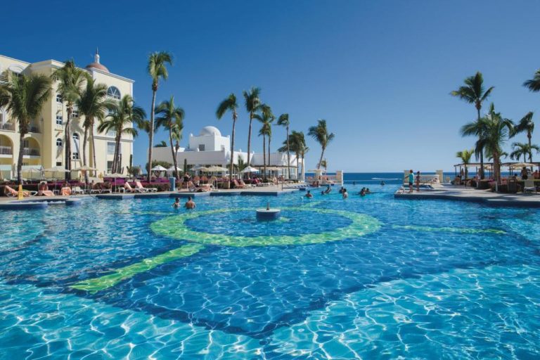 Piscina exterior con vistas al mar del Riu Palace Cabo San Lucas All Inclusive rodeada de palmeras