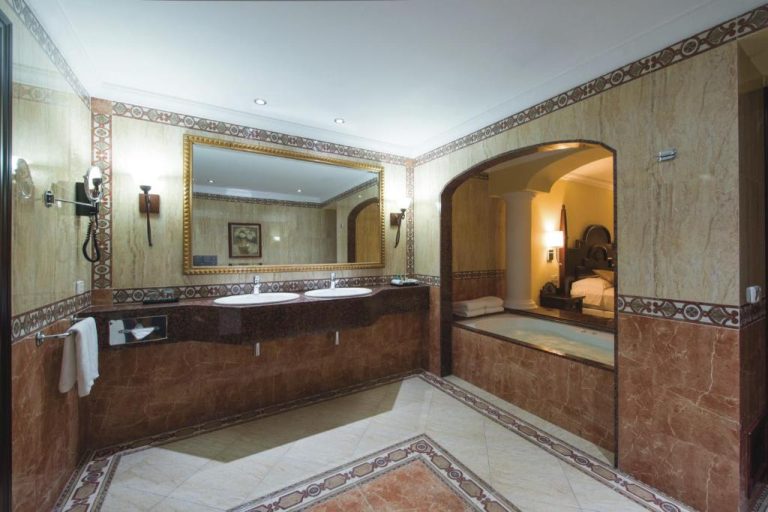 Lujoso baño con jacuzzi y doble lavabo de mármol en el Riu Palace Cabo San Lucas All Inclusive