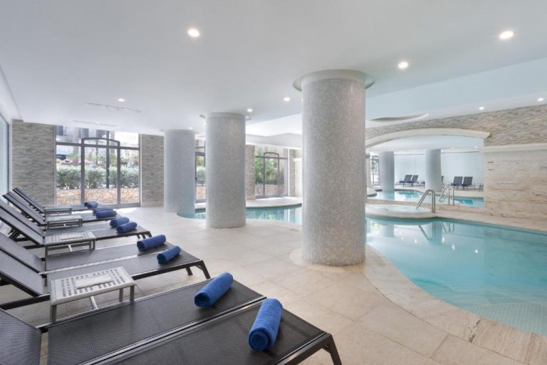 Piscina interior con tumbonas y columnas decorativas del Maritim Antonine Hotel & Spa