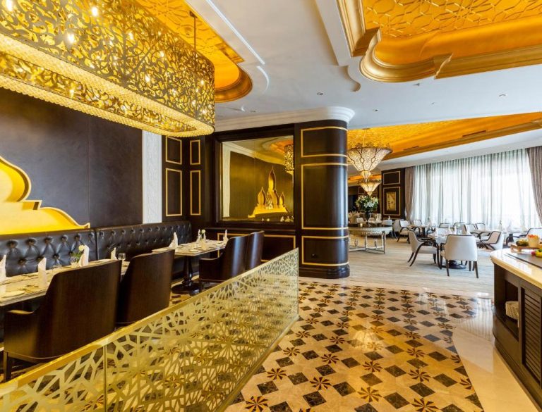 Elegante restaurante del Ezdan Palace Hotel con decoración dorada arabesca y suelo de mármol