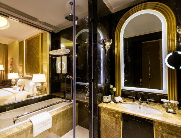 Lujoso baño de mármol negro y dorado con bañera y ducha en Ezdan Palace Hotel