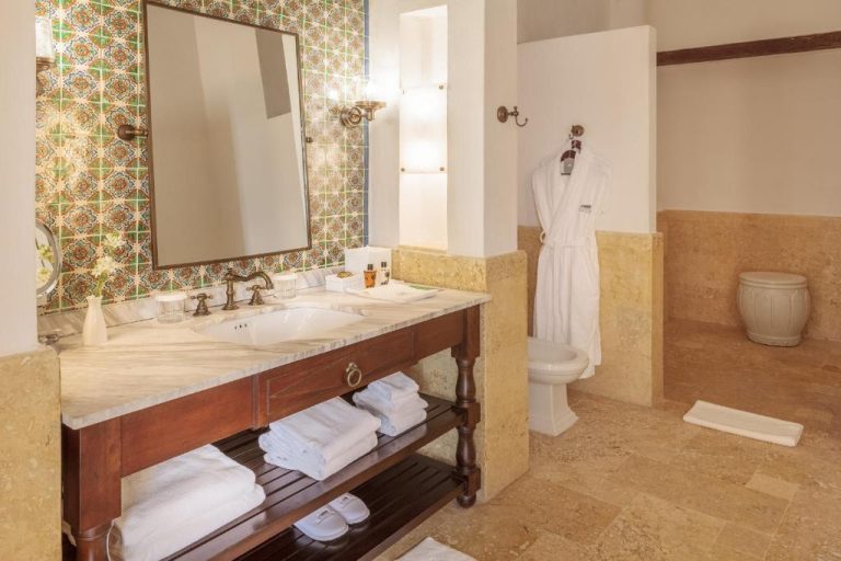 Baño de lujo con mármol, azulejos decorativos y albornoz en Hotel Casa San Agustín Cartagena
