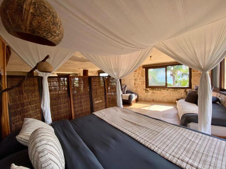 Habitación con cama dosel y mosquitera en Sueños Tulum con vista al mar y decoración rústica