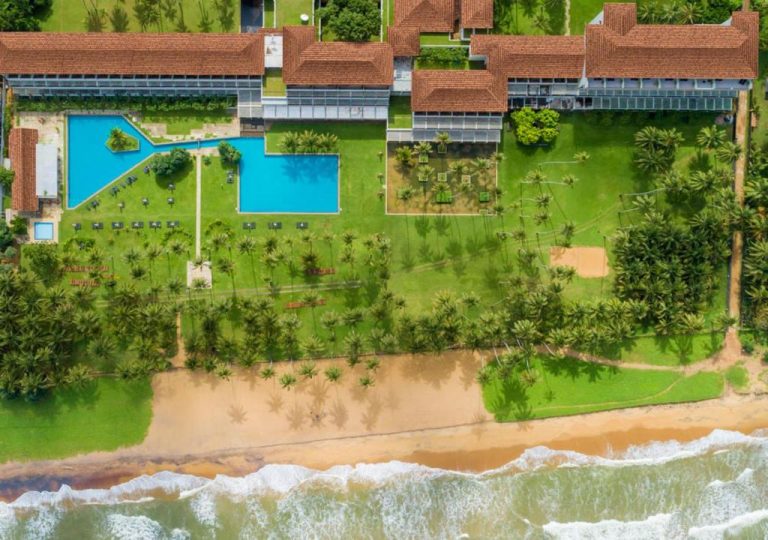 Vista aérea del Blue Water Geoffrey Bawa Heritage Resort con piscinas, jardines tropicales y playa privada