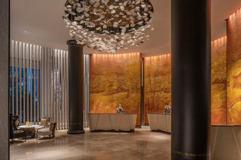Recepción principal del Four Seasons Bangkok con lujosa araña de cristal y murales dorados decorativos