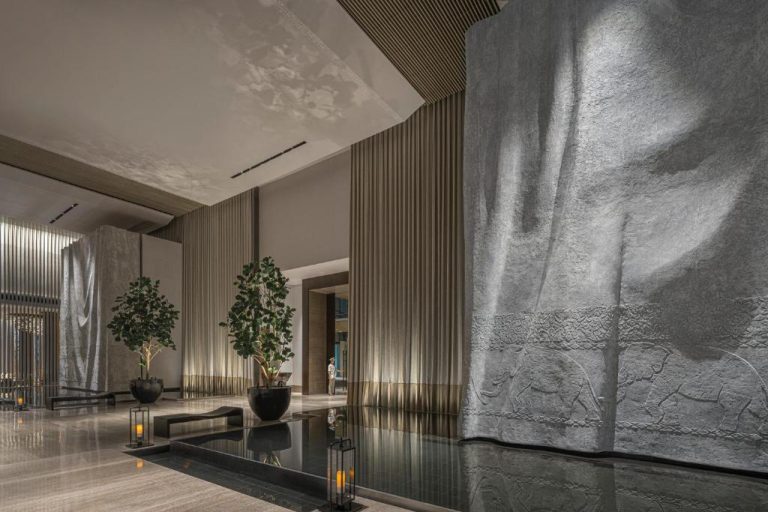 Lujoso lobby del Four Seasons Bangkok con escultura de piedra tallada y árboles decorativos junto al río Chao Phraya
