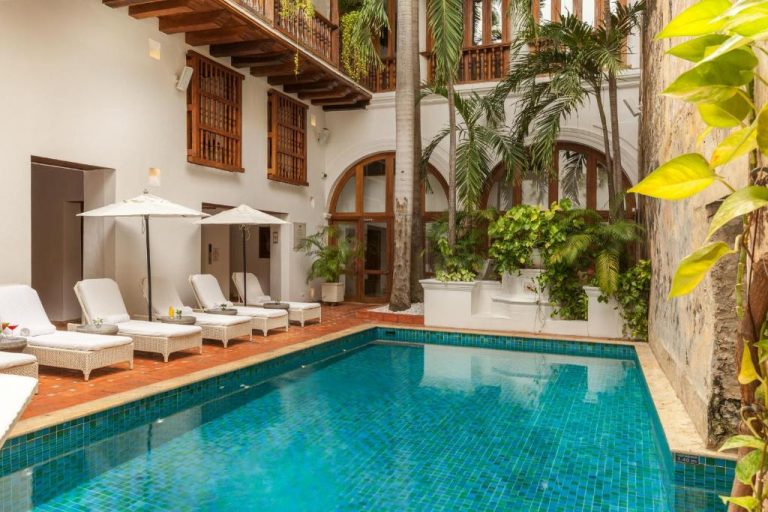 Piscina interior con tumbonas y palmeras en el Hotel Casa San Agustín de Cartagena de Indias
