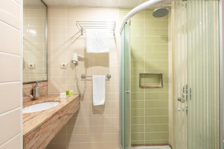 Baño moderno con ducha de hidromasaje y encimera de mármol en el Hotel Ilayda