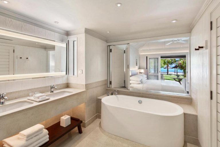 Baño de lujo con bañera exenta y vistas al dormitorio y playa en LUX* Le Morne Resort Mauricio