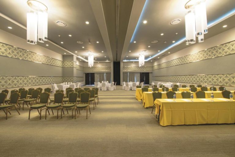 Salón de eventos y conferencias con mesas amarillas y sillas verdes en el Riu Palace Cabo San Lucas