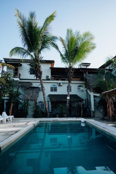 Piscina exterior con palmeras tropicales frente a la Residencia El Balatà de dos plantas