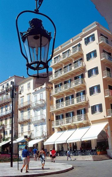 Fachada exterior del Arcadion Hotel con terraza y farola clásica en la plaza de Corfú, Grecia