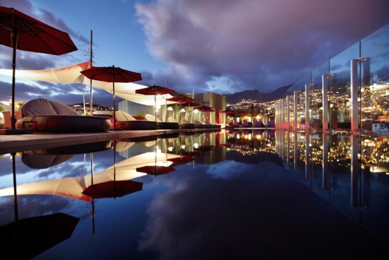 Piscina infinita con vistas nocturnas a la ciudad en The Vine Hotel Madeira