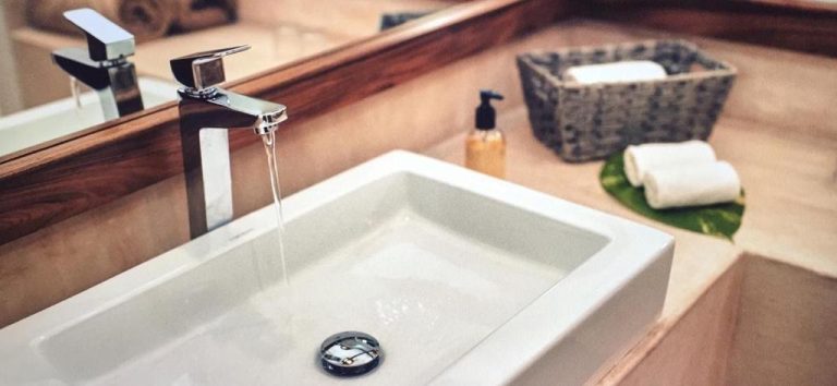 Lavabo de diseño moderno con grifo cromado y amenities en el baño de Casa Altamar