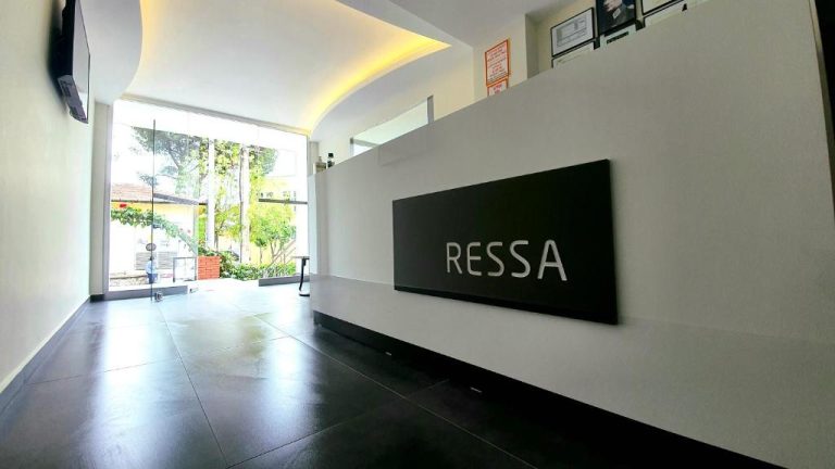 Recepción moderna del Ressa Apart con mostrador blanco y acceso principal con luz natural