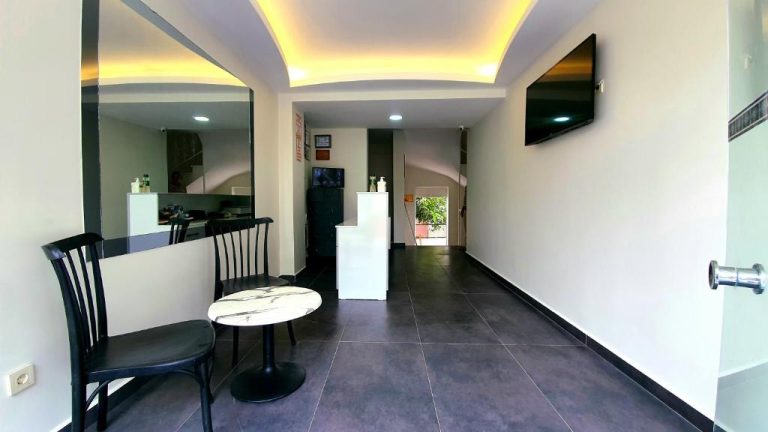 Sala común con mesa de mármol, sillas negras y televisión en pared del Ressa Apart