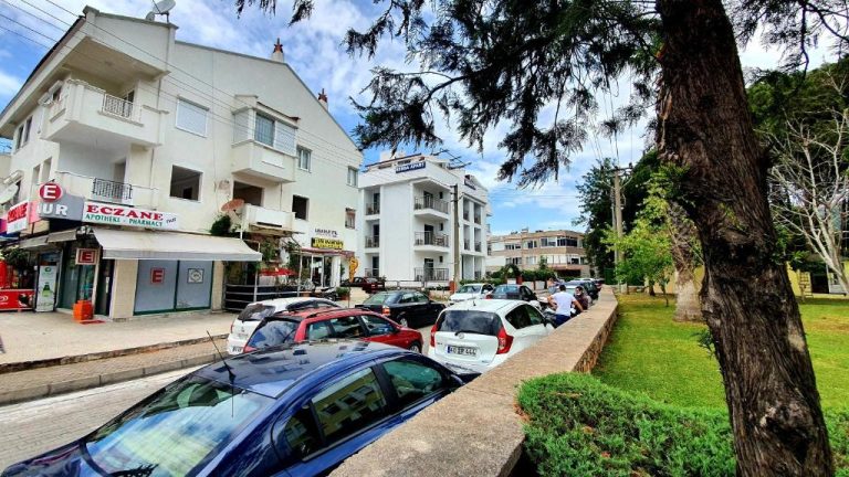 Vista exterior del Ressa Apart con aparcamiento y farmacia en primer plano en zona residencial