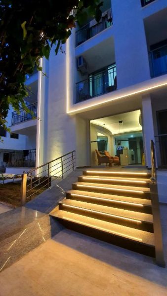 Entrada principal iluminada con escaleras del Ressa Apart, edificio moderno con luces LED nocturnas
