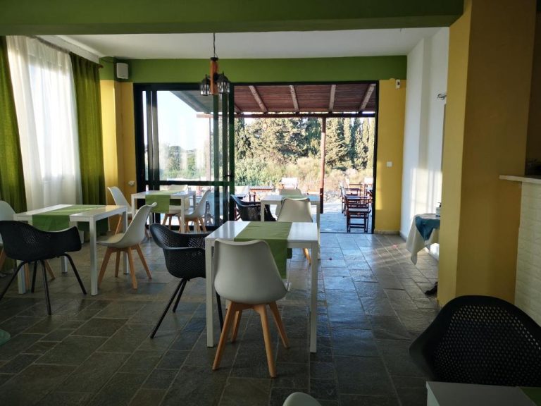 Restaurante interior con mesas blancas y terraza exterior del Hotel Ilios and Irene