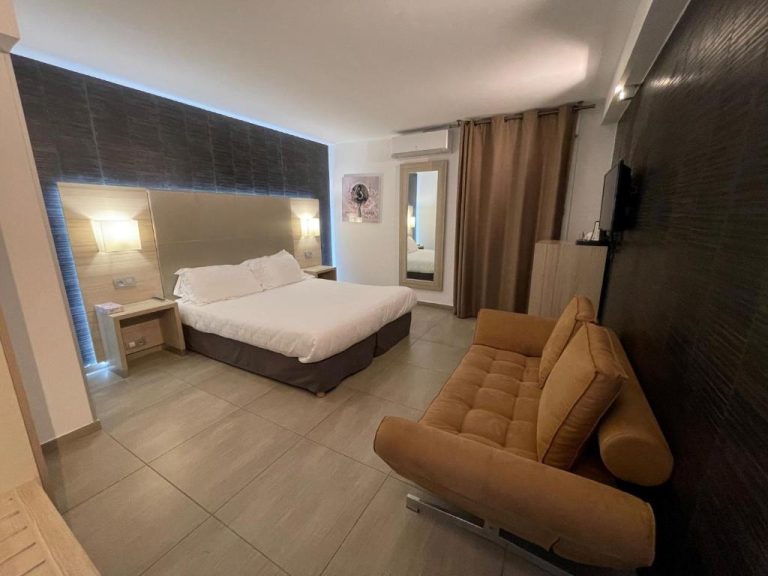 Habitación doble moderna con cama y sofá en el Hôtel L'Escale Coté Port