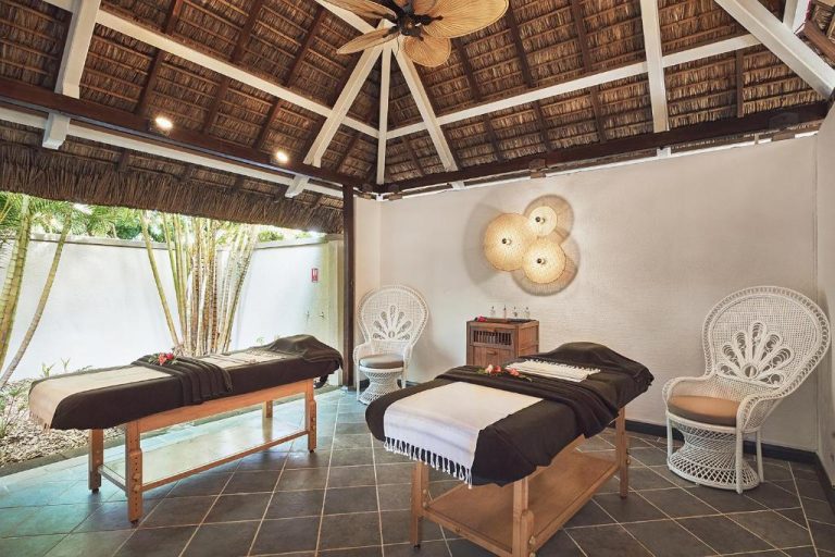 Sala de masajes con dos camillas y techo de palapa en Paradise Cove Boutique Hotel Adults Only