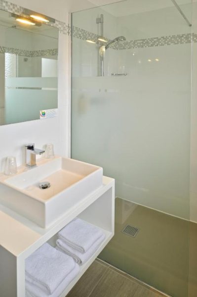 Baño moderno con ducha de cristal y lavabo blanco en Hôtel L'Escale Côté Port