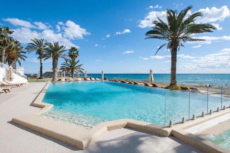 Piscina infinita con vistas al mar del Hotel Bel Azur Thalasso & Bungalows rodeada de palmeras