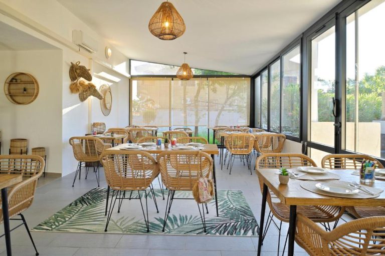 Restaurante interior con sillas de ratán y mesas de madera en el Hôtel L'Escale Côté Port