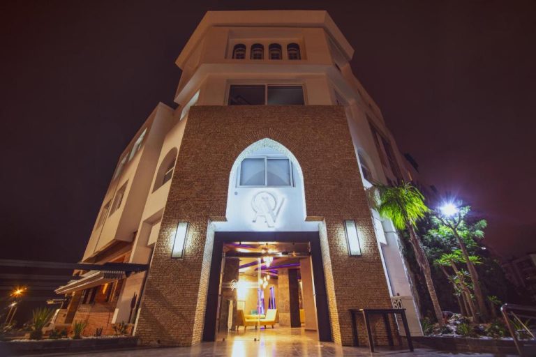 Fachada exterior iluminada de noche del Hotel Ocean Atlantic View con entrada de arco árabe en Agadir