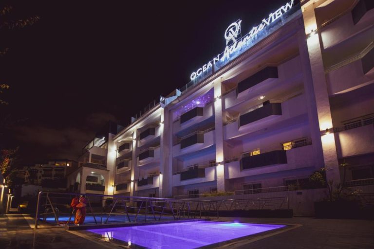 Piscina iluminada de noche con vista a la fachada del Ocean Atlantic View Hotel