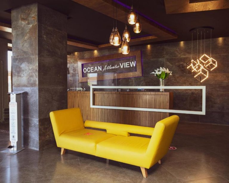 Recepción moderna con sofá amarillo y lámparas decorativas del hotel Ocean Atlantic View