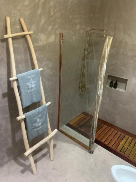Baño de lujo con ducha dorada y escalera de toallas en Thari Fushi Luxury Maldives