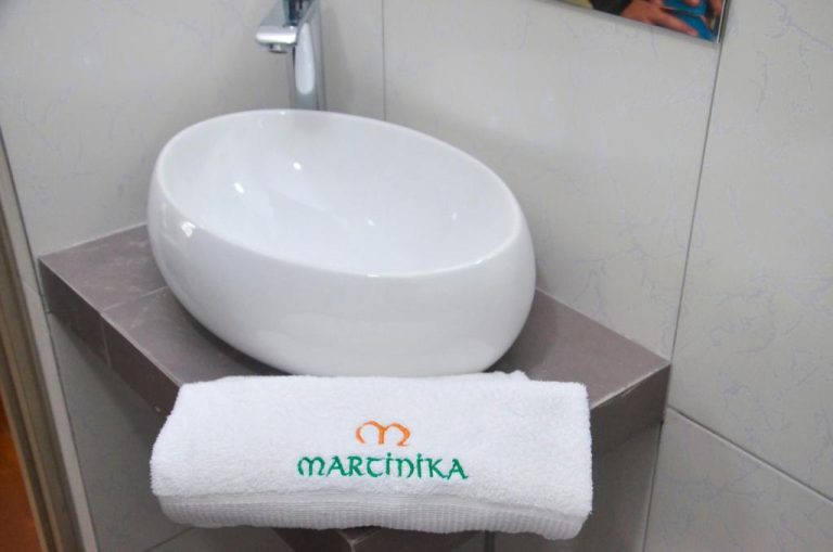 Baño moderno con lavabo de porcelana y toalla bordada del Hotel Martinika