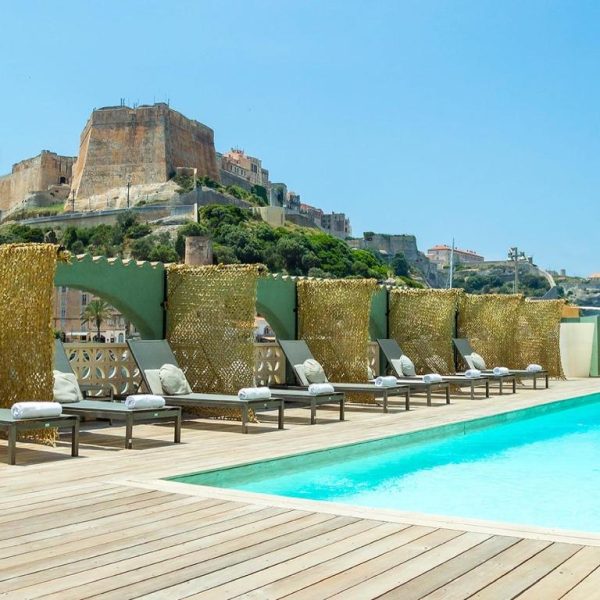 Piscina exterior con tumbonas y vistas a la ciudadela histórica en el Hotel Solemare