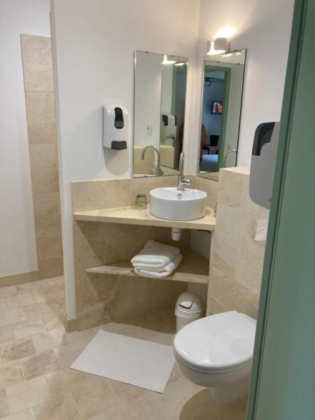 Baño moderno con lavabo redondo y espejo del Logis Hôtel Les Tilleuls, con inodoro y toallas blancas