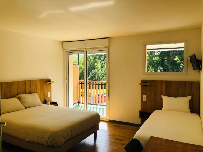 Habitación doble con dos camas y balcón con vistas a la naturaleza en Logis Hôtel Les Tilleuls