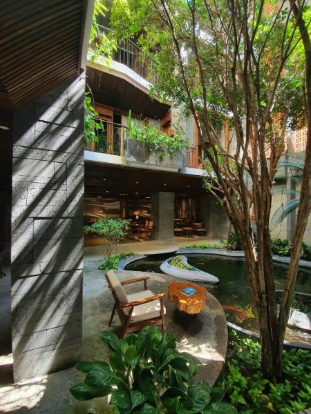 Jardín interior con estanque, vegetación tropical y zona de descanso en el Minh Boutique Hotel